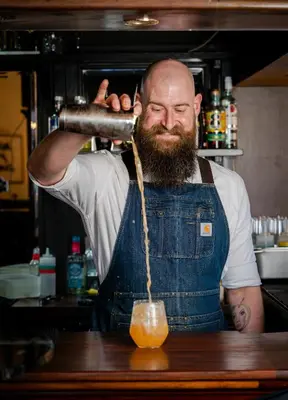 a man in a kitchen making a drink at The King Of Prussia in Fowey