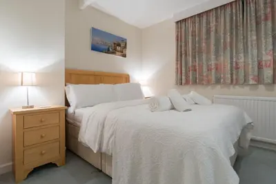 a bedroom with two beds with white sheets and a window at Talland Croft in Crantock