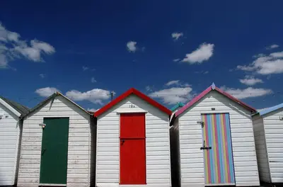 a row of four beach huts with colorful doors at Talland Croft in Crantock