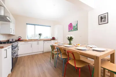 a kitchen and dining room with a wooden table and chairs at Talland Croft in Crantock