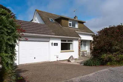 a house with a white garage with a roof at Talland Croft in Crantock