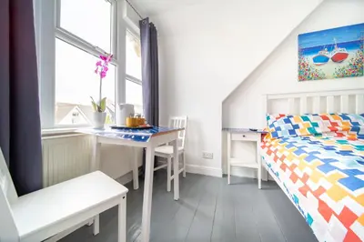 a bedroom with a bed and a desk and a table at Tolcarne Guest House in Newquay