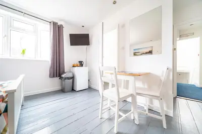 a white dining room with a table and chairs at Tolcarne Guest House in Newquay