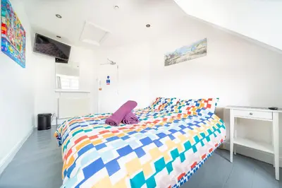 a bedroom with a bed with a colorful comforter at Tolcarne Guest House in Newquay