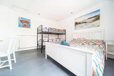 a white bedroom with a bunk bed and a desk at Tolcarne Guest House in Newquay