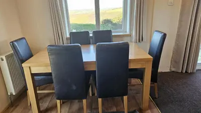 a dining room table with chairs and a window at Penmor in Bude