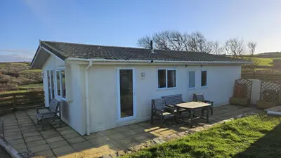 a small white house with a table and chairs at Penmor in Bude