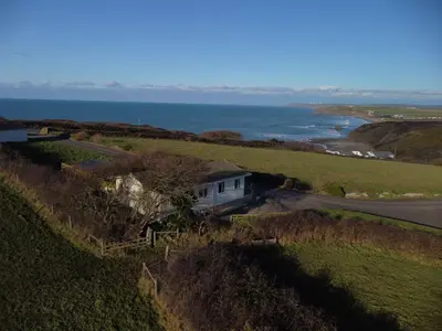 an aerial view of a house on a hill next to the ocean at Penmor in Bude