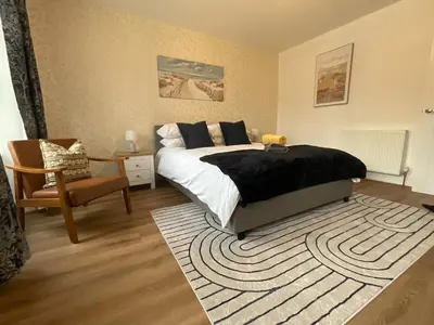 a bedroom with a bed and a chair and a rug at Gregory Flats No. 1, by HomeInspire in Looe