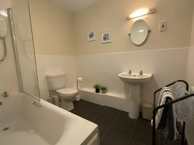 a bathroom with a sink and a toilet and a mirror at Gregory Flats No. 1, by HomeInspire in Looe