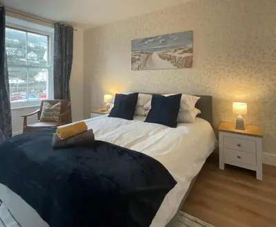 a bedroom with a large bed and a window at Gregory Flats No. 1, by HomeInspire in Looe