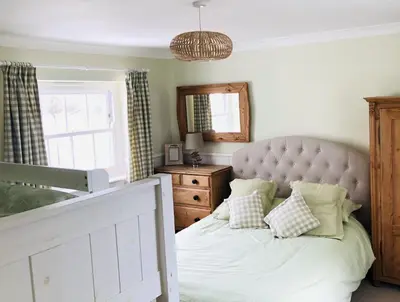 a bedroom with a bed and a mirror and a window at St Edwards Cottage, Tintagel in Tintagel