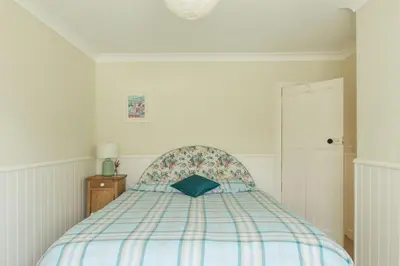 a bedroom with a bed with a blue pillow on it at St Edwards Cottage, Tintagel in Tintagel