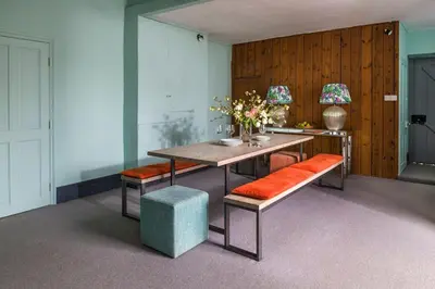 a dining room with a wooden table and orange seats at Lostwithiel Stable House in Braddock
