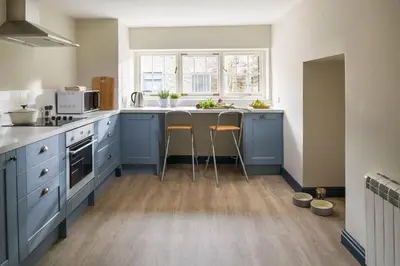 a kitchen with blue cabinets and a counter with stools at Lostwithiel Stable House in Braddock