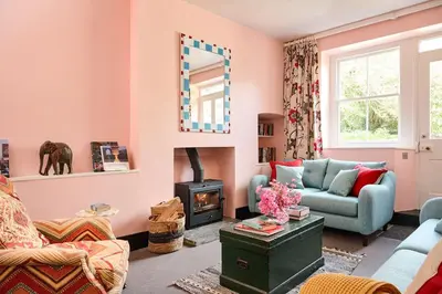 a living room with pink walls and a mirror at Lostwithiel Dairy House in Braddock