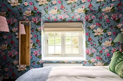 a bedroom with a window and a flowery wallpaper at Lostwithiel Dairy House in Braddock