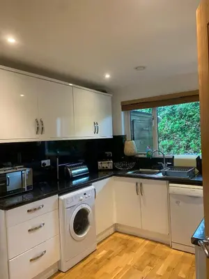 a kitchen with white cabinets and a washing machine at Valentyne Beach House in Porthtowan