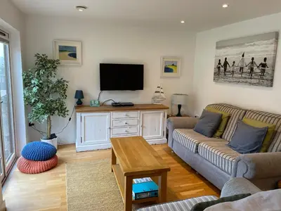 a living room with a couch and a flat screen tv at Valentyne Beach House in Porthtowan