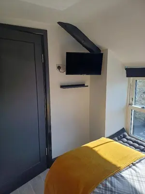 a bedroom with a bed and a tv on the wall at Commercial Inn in Saint Dennis