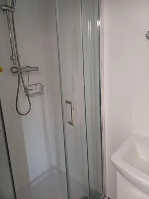 a shower with a glass door next to a toilet at Commercial Inn in Saint Dennis