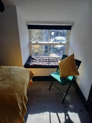 a room with a bed and a window with a chair at Commercial Inn in Saint Dennis