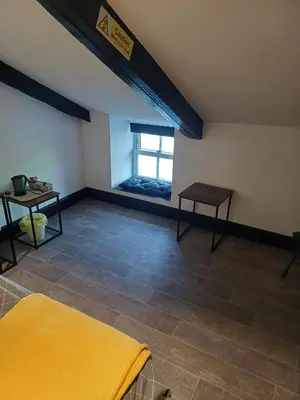 an attic room with a yellow bed and a window at Commercial Inn in Saint Dennis