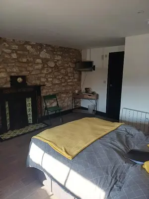a bedroom with a bed and a stone wall at Commercial Inn in Saint Dennis