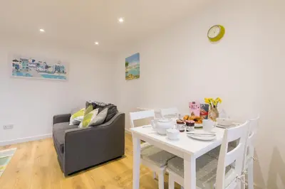 a dining room with a white table and a couch at Whitecaps in St Ives