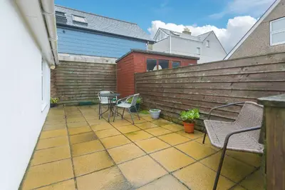 a patio with chairs and a table and a fence at Whitecaps in St Ives