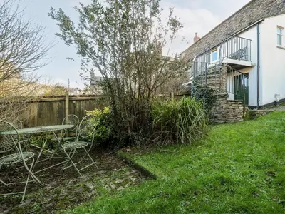 a yard with a table and chairs and a building at Lowen Cottage in Boscastle