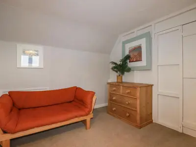 a living room with a orange couch and a dresser at Lanvean Farmhouse in Newquay