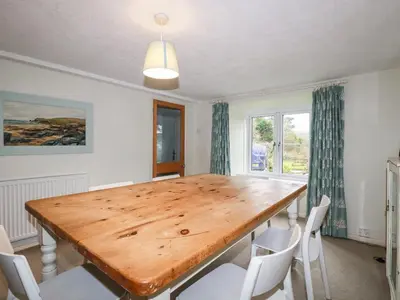 a dining room with a wooden table and chairs at Lanvean Farmhouse in Newquay