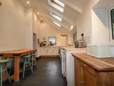 a kitchen with white cabinets and a wooden table at Lanvean Farmhouse in Newquay