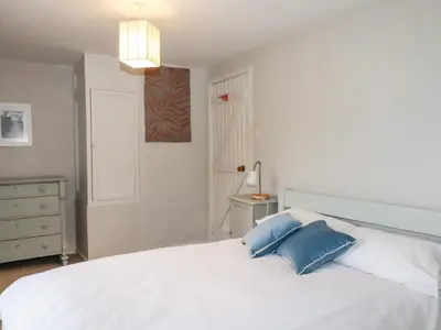 a bedroom with a white bed with two blue pillows at Lanvean Farmhouse in Newquay