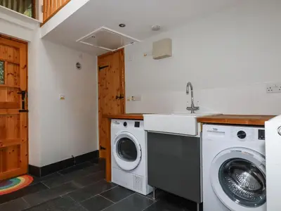 a kitchen with a washing machine and a sink at Lanvean Farmhouse in Newquay
