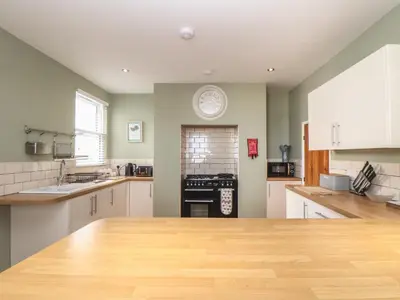 a large kitchen with white cabinets and a clock on the wall at The Mordon in Newquay