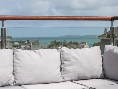 a couch with white pillows sitting on a balcony at The Mordon in Newquay