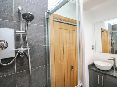 a shower with a wooden door in a bathroom at Rooftops in St Ives