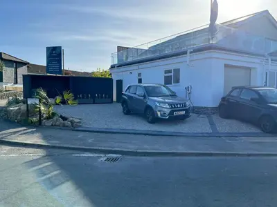 two cars parked in front of a white house at Porthkidney Suite, Carbis Bay, St Ives, free parking, near beach in Carbis Bay