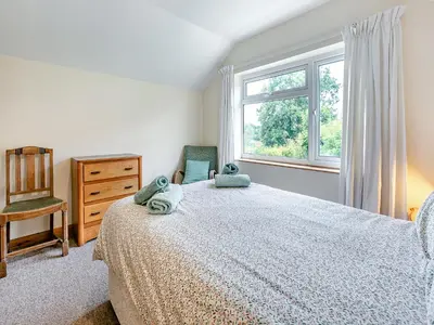 a bedroom with a bed and a window and a chair at Country View in Saint Erth