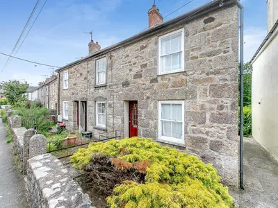 a brick house with a red door and some bushes at Country View in Saint Erth
