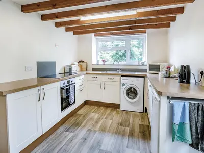 a kitchen with white cabinets and a washer and dryer at Country View in Saint Erth