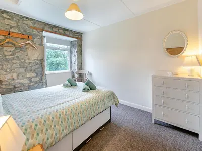 a bedroom with a bed and a stone wall at Country View in Saint Erth