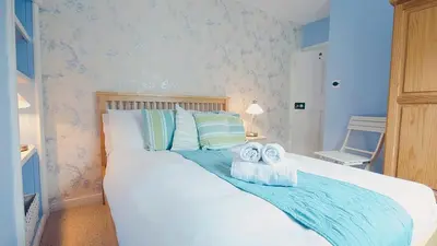 a bedroom with a white bed with towels on it at A Cosy Period Family Cottage in St Ives Town, sleeps 4, pet friendly in St Ives