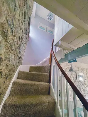 a staircase in a house with a stone wall at A Cosy Period Family Cottage in St Ives Town, sleeps 4, pet friendly in St Ives