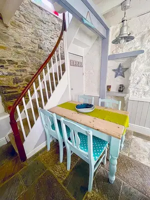 a wooden table with two chairs and a staircase at A Cosy Period Family Cottage in St Ives Town, sleeps 4, pet friendly in St Ives