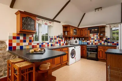 a large kitchen with wooden cabinets and a black counter top at Lanjew Park in Bodmin
