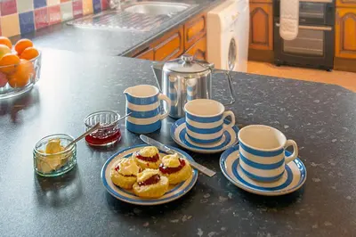 a kitchen counter with two plates of food and cups at Lanjew Park in Bodmin