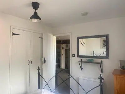 a hallway with a door and a mirror at Horseshoe Cottage in Looe